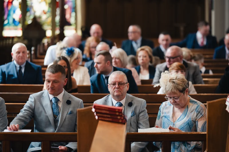 a group of people sitting in a church waiting for the bride and groom to walk down the aisle