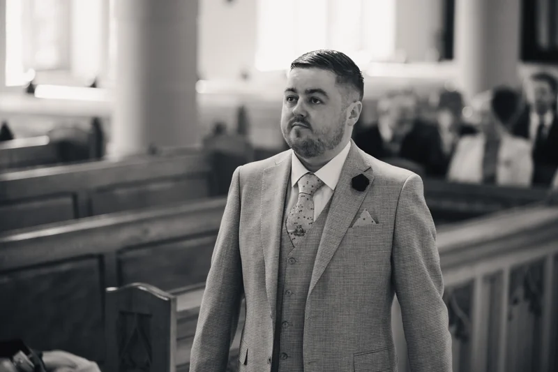 a man in a suit walking down the aisle of a church