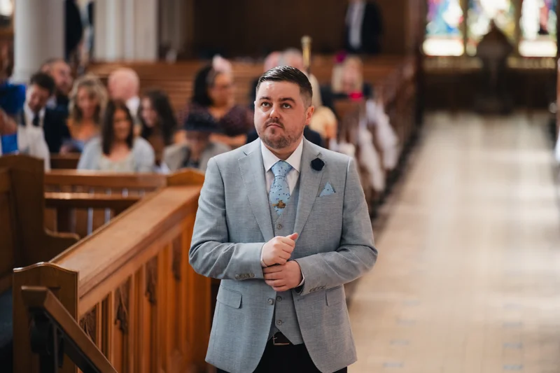 a man in a suit walking down the aisle of a church