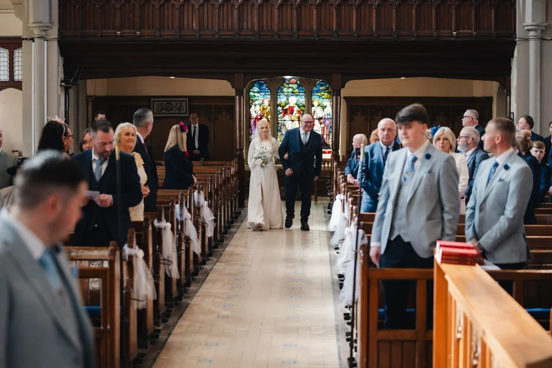 a bride and groom walking down the aisle of a church