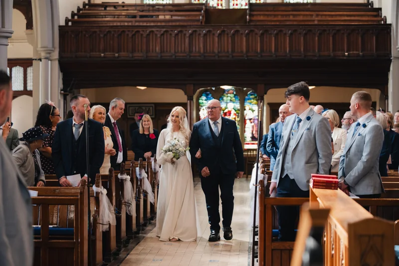 a bride and groom walk down the aisle of a church