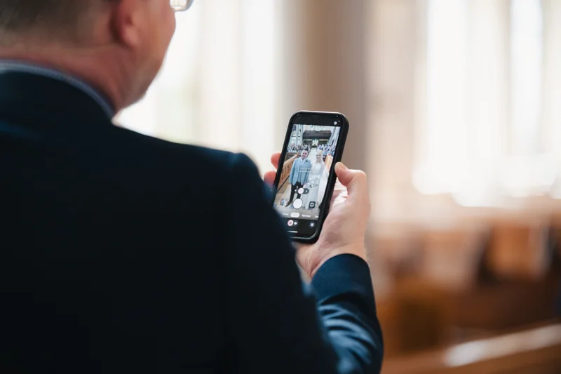 a man in a suit and tie takes a photo with his cell phone