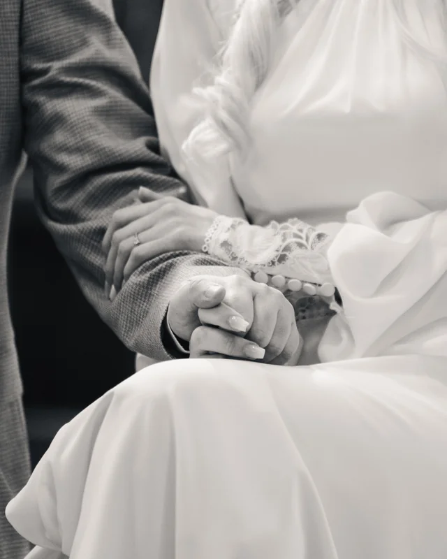black and white image of bride and groom holding hands in a wedding ceremony