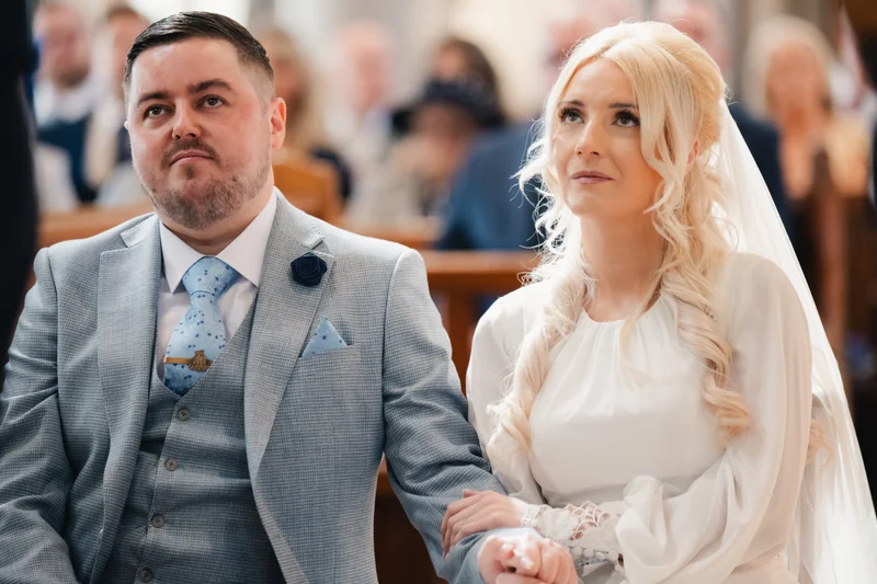 a bride and groom look at each other as they walk down the aisle
