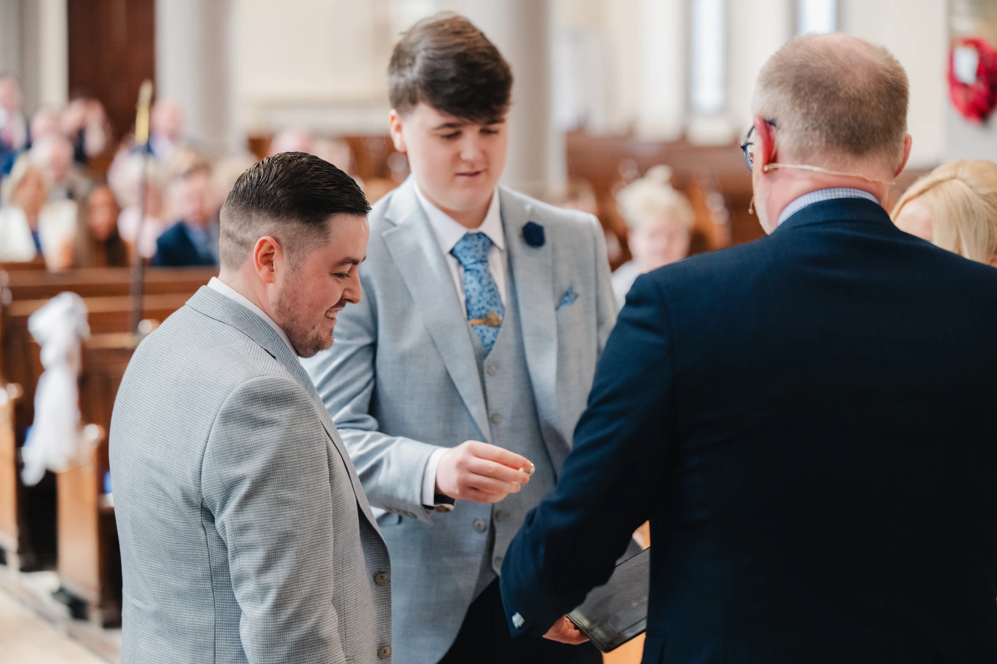 a man in a suit and tuxedo walks down the aisle of a church