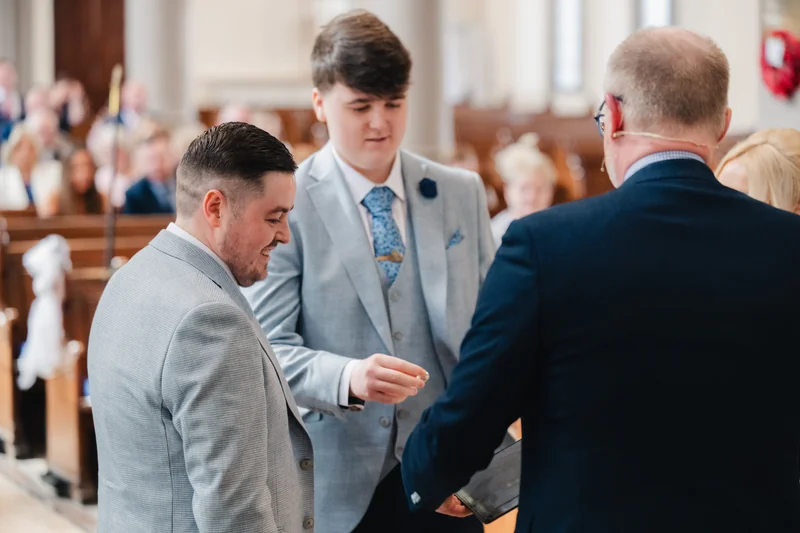 a man in a suit and tuxedo walks down the aisle of a church