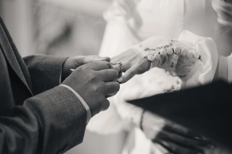 a bride puts her wedding ring on her husband's finger