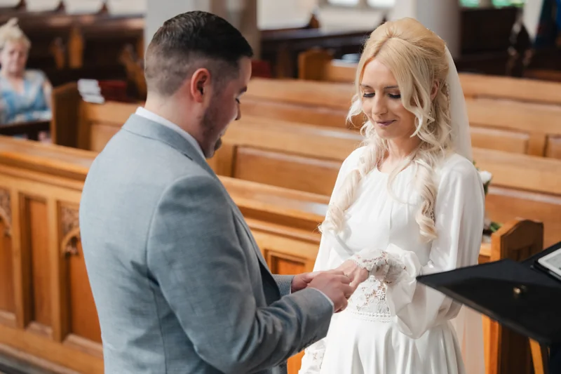 a bride and groom exchange their wedding rings in a church
