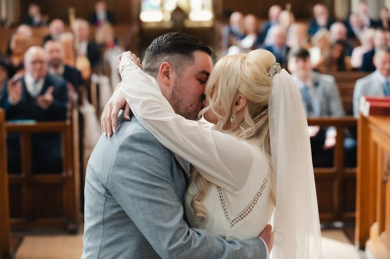 a bride and groom kiss in the middle of a church during their wedding ceremony