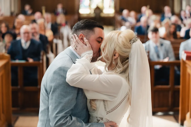 a bride and groom kiss in a church during their wedding ceremony