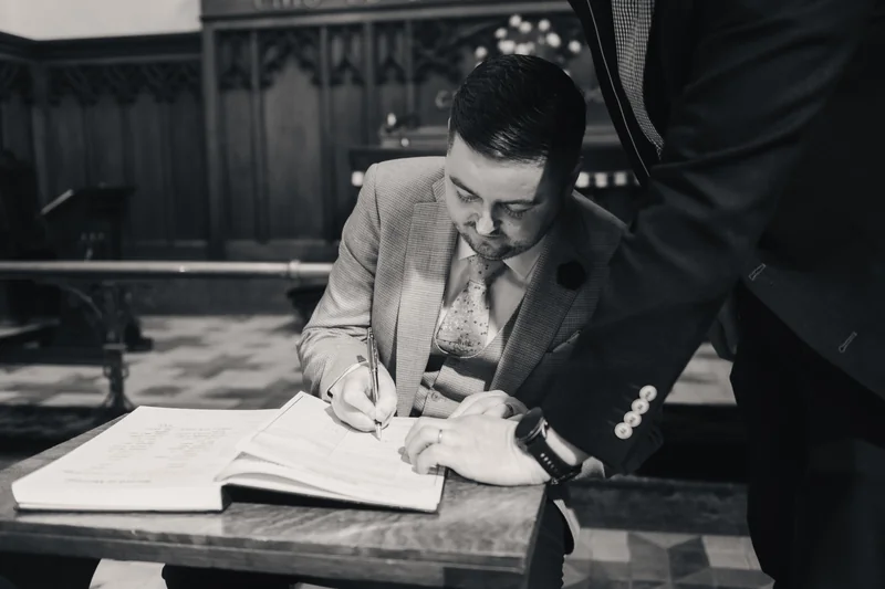 a man is writing on a piece of paper with a pen in his hand