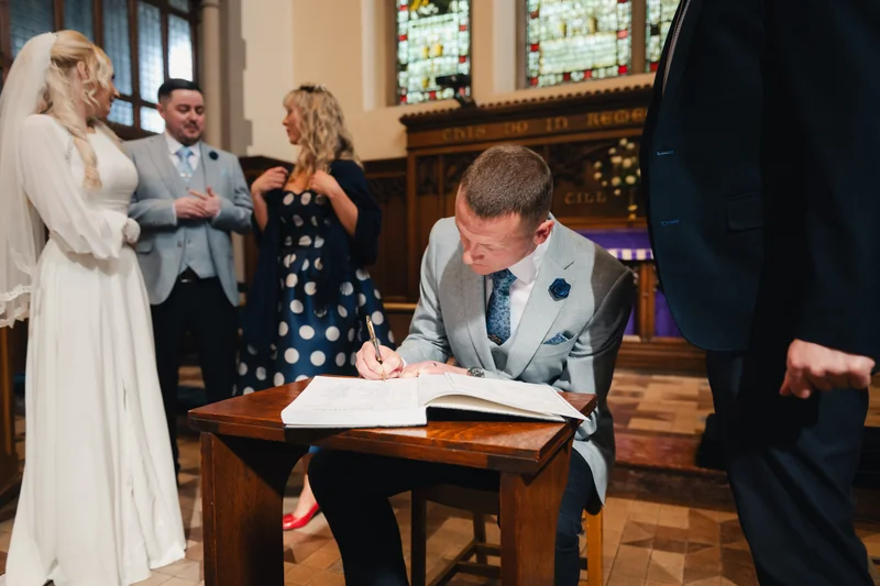 a bride and groom signing a wedding book in a church