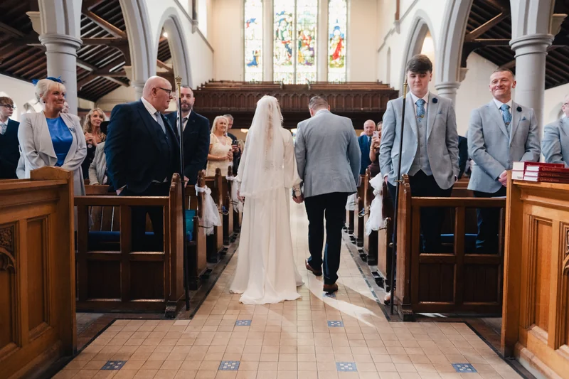 a bride and groom walking down the aisle of a church
