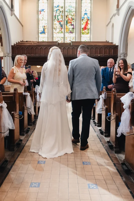 a bride and groom walk down the aisle of a church