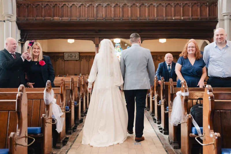 a bride and groom walk down the aisle of a church