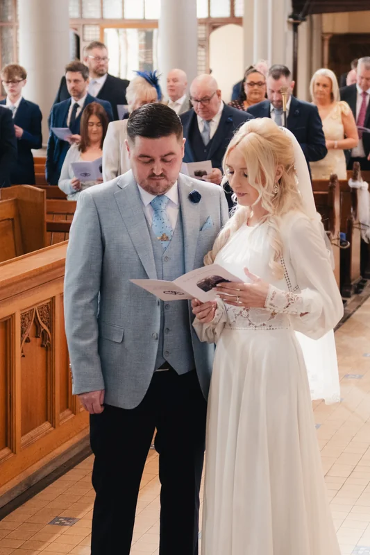 a bride and groom read their wedding vows in a church
