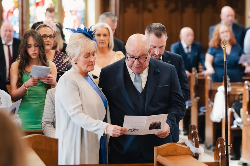 a man in a suit and tie walks down the aisle of a church