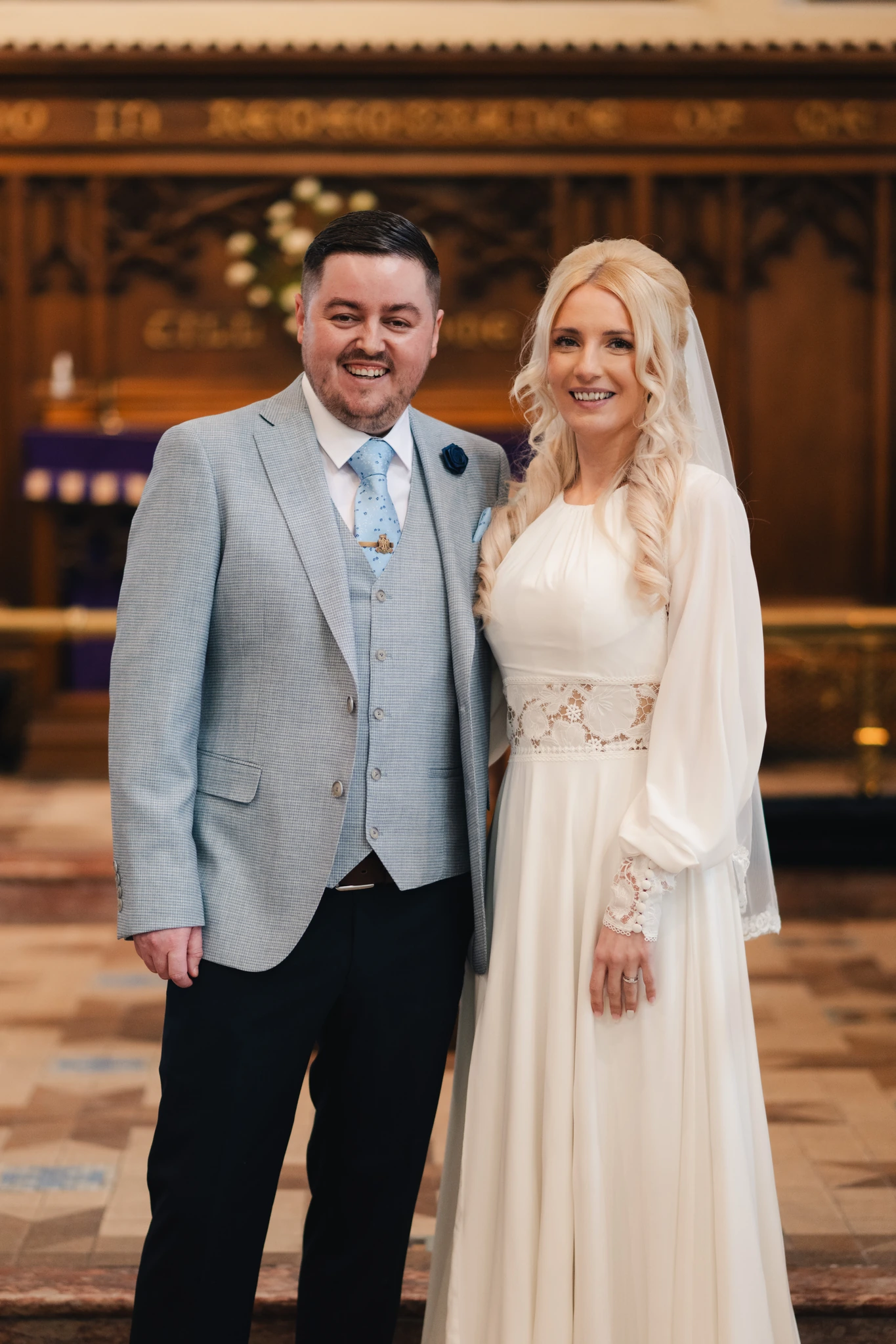 a bride and groom pose for a photo in a church