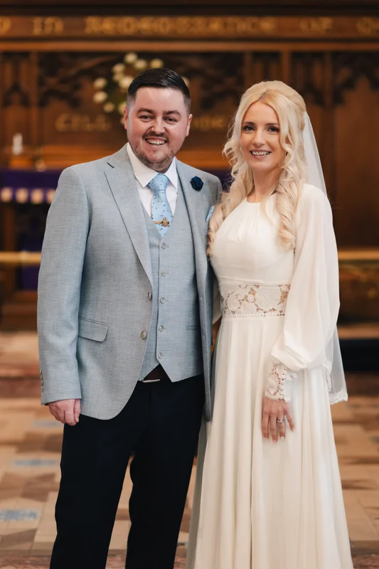 a bride and groom pose for a photo in a church