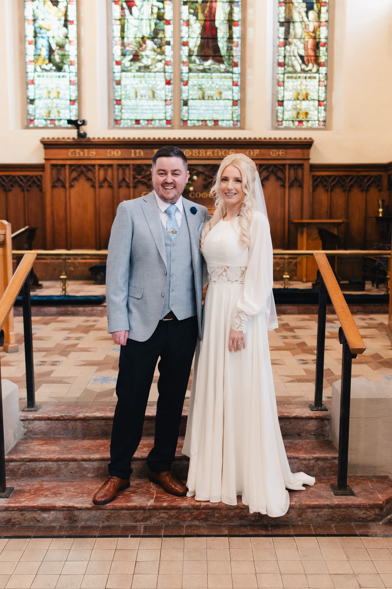 a bride and groom standing in front of a stained glass window