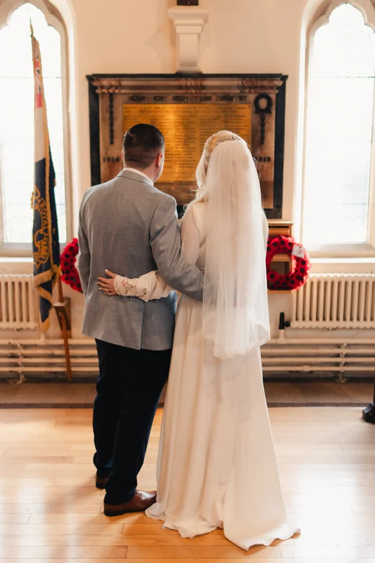 a bride and groom stand in front of a fireplace in their wedding ceremony