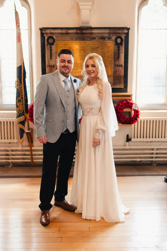 a bride and groom pose for a photo in front of their wedding venue
