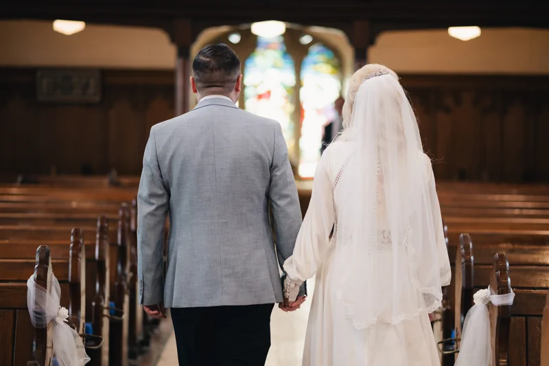 a bride and groom walk down the aisle of a church