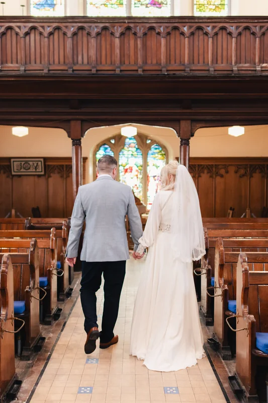 a bride and groom walk down the aisle of a church