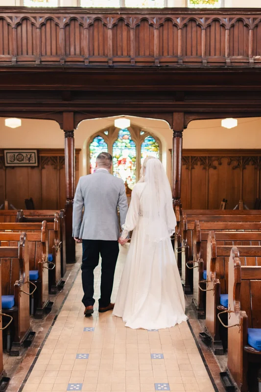 a bride and groom walk down the aisle of a church