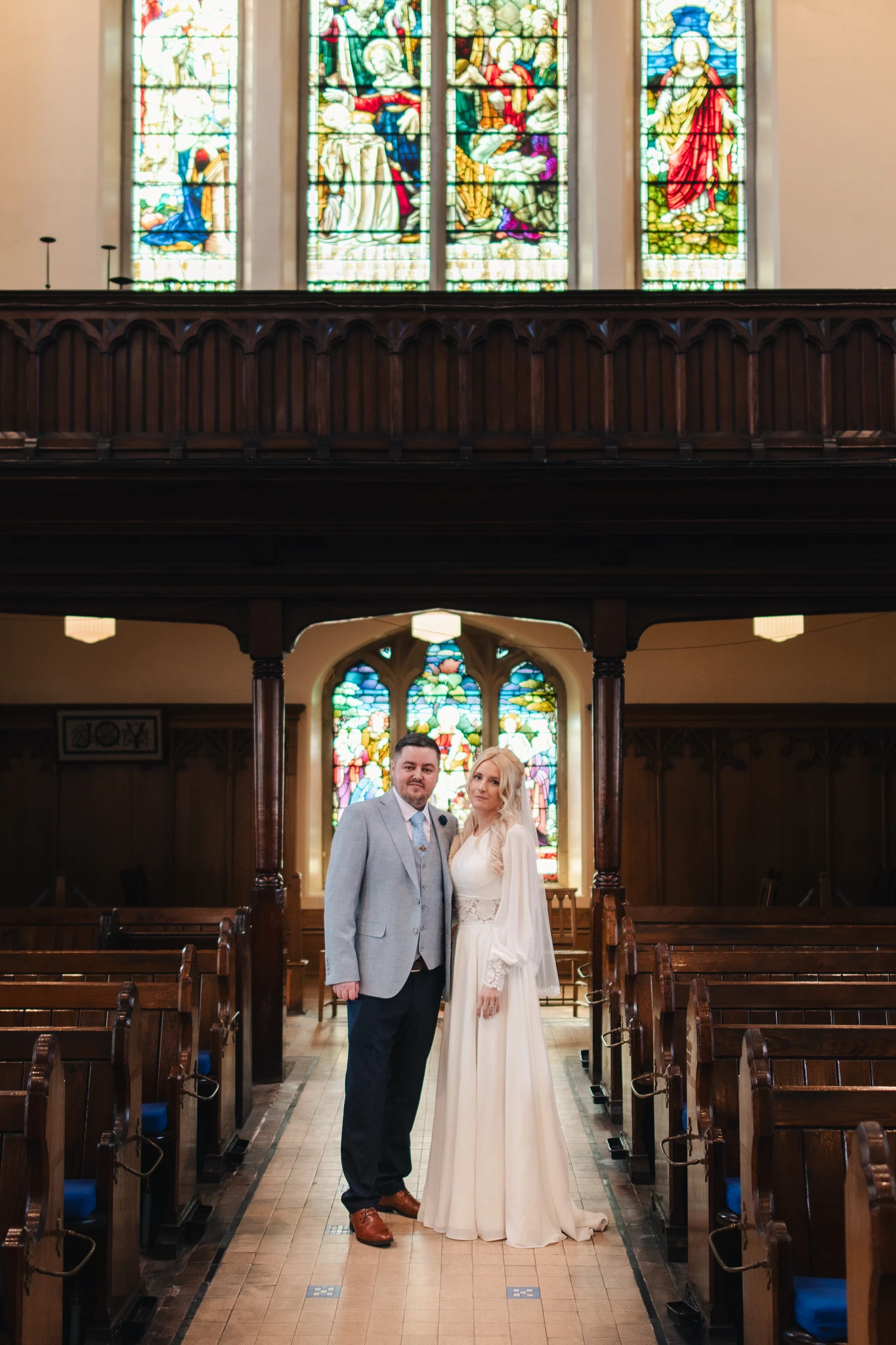 a bride and groom standing in front of a stained glass window