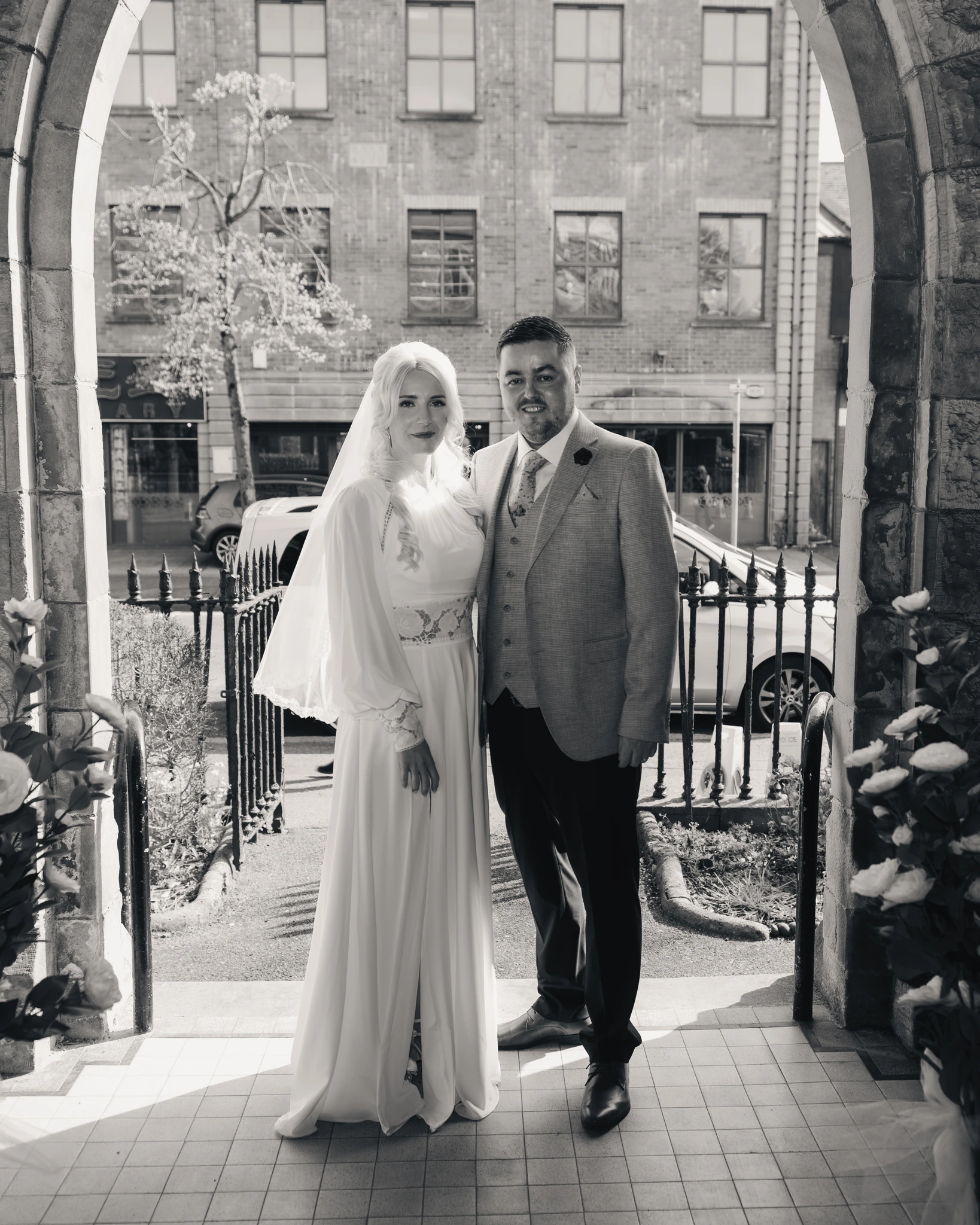 a bride and groom standing in front of an archway