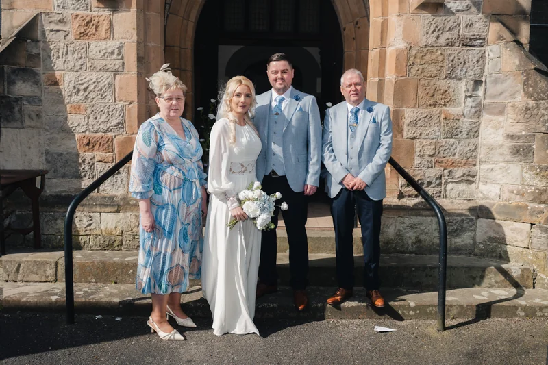 a bride and groom pose in front of a church