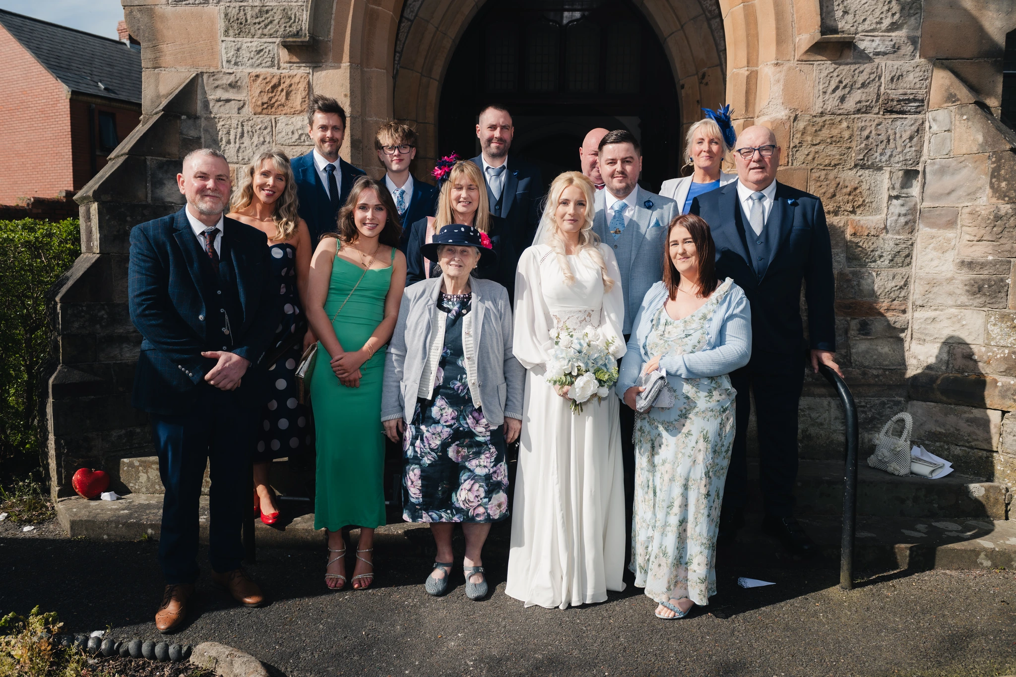 a bride and groom pose with their wedding party in front of a church