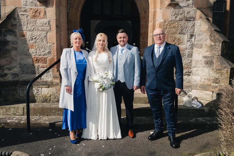 a bride and groom pose in front of a church