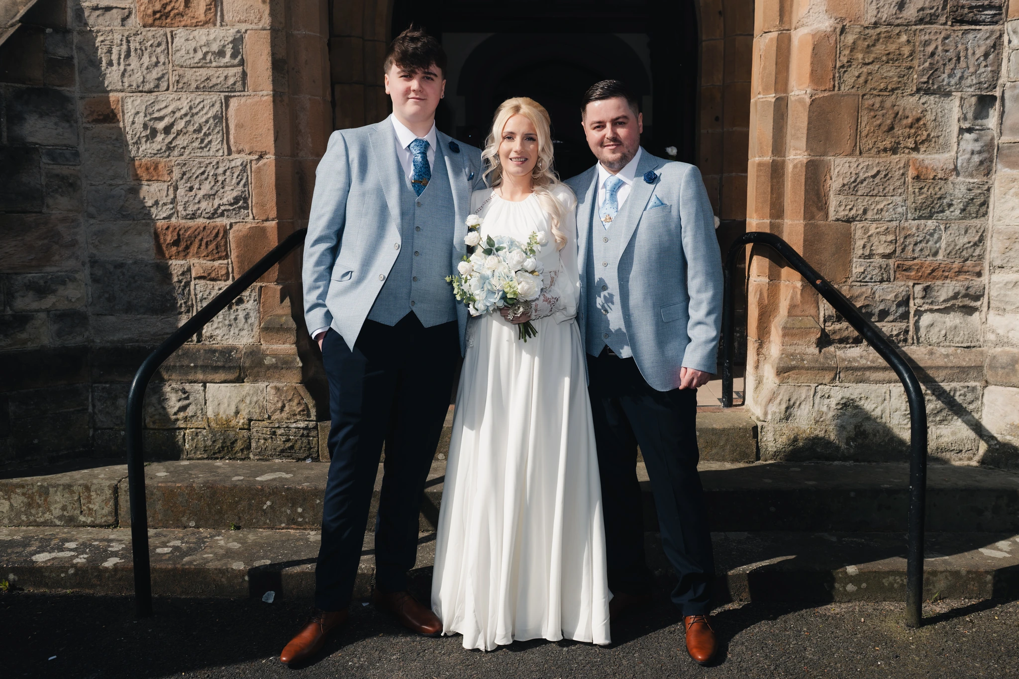 a bride and groom pose in front of a church