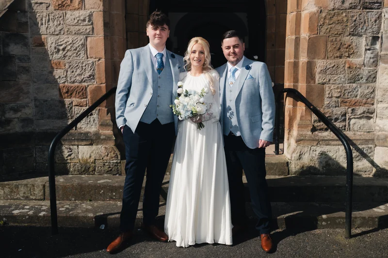 a bride and groom pose in front of a church