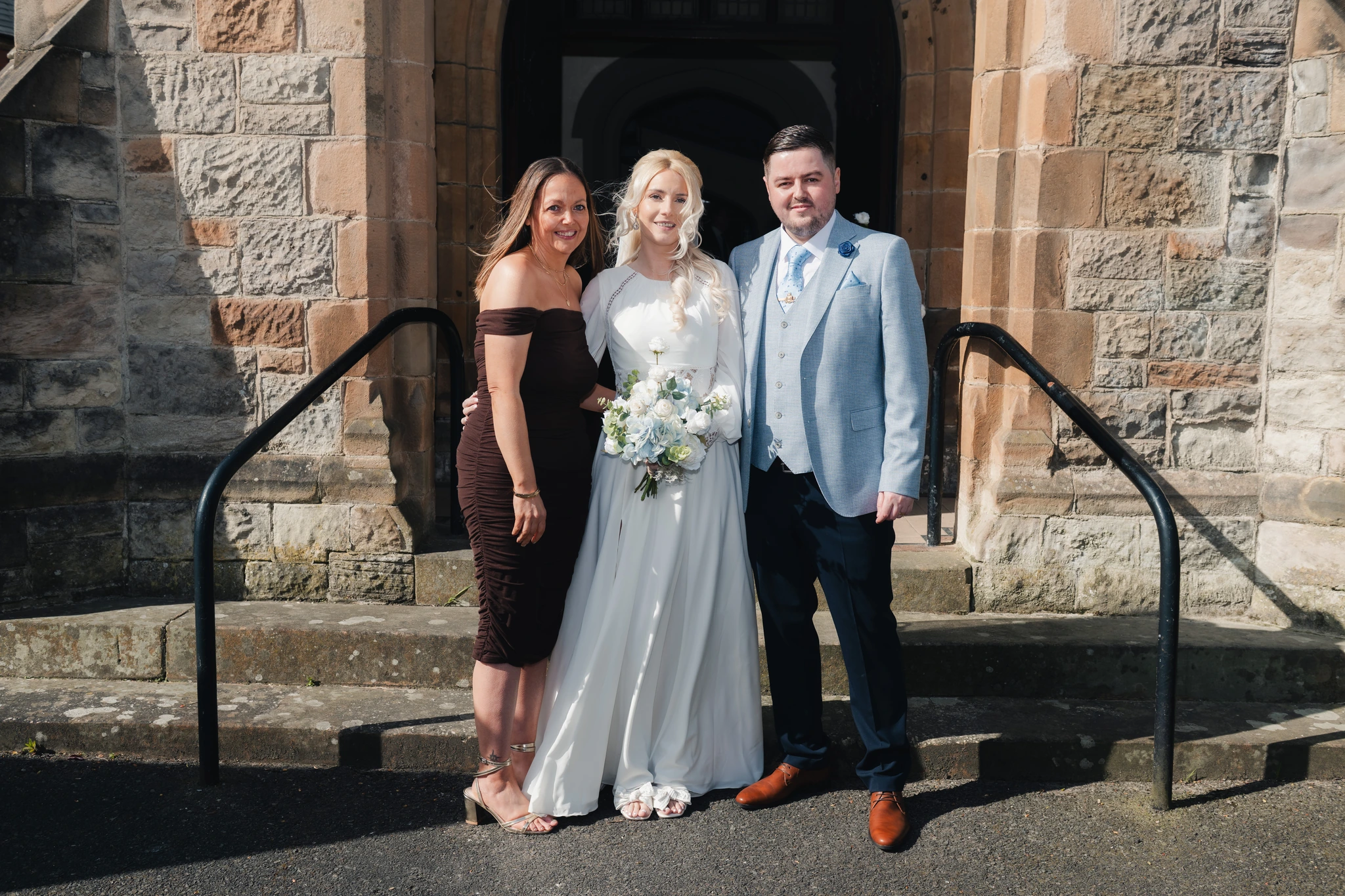 a bride and groom pose in front of a church