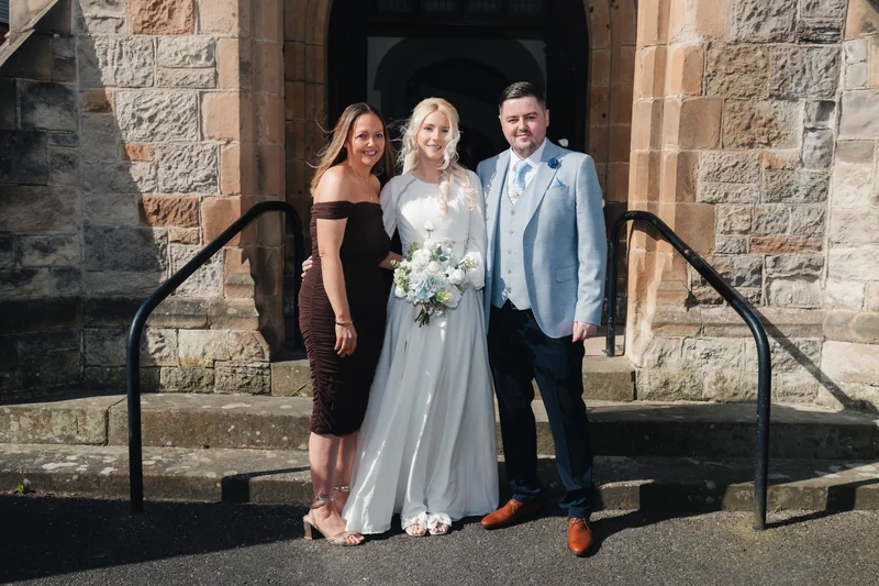 a bride and groom pose in front of a church