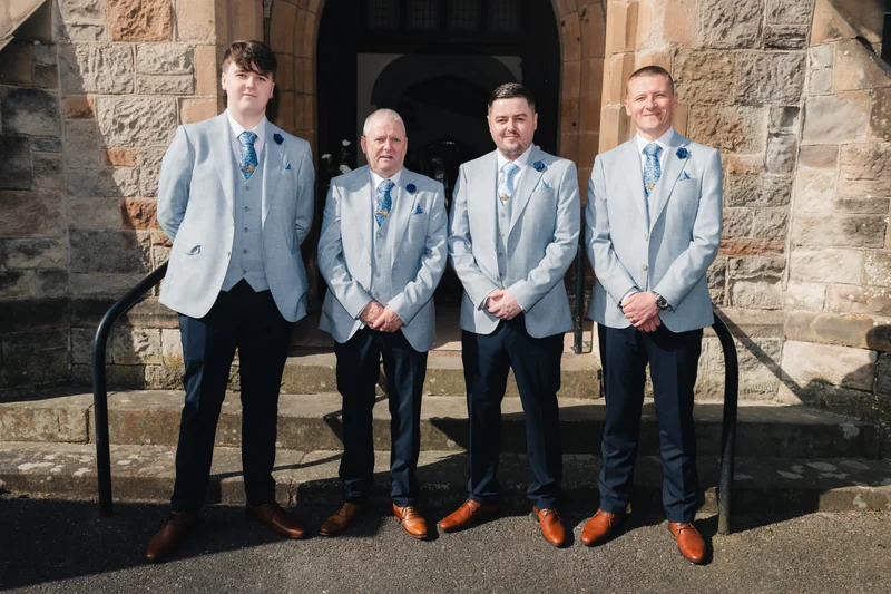 a group of grooms standing in front of a church