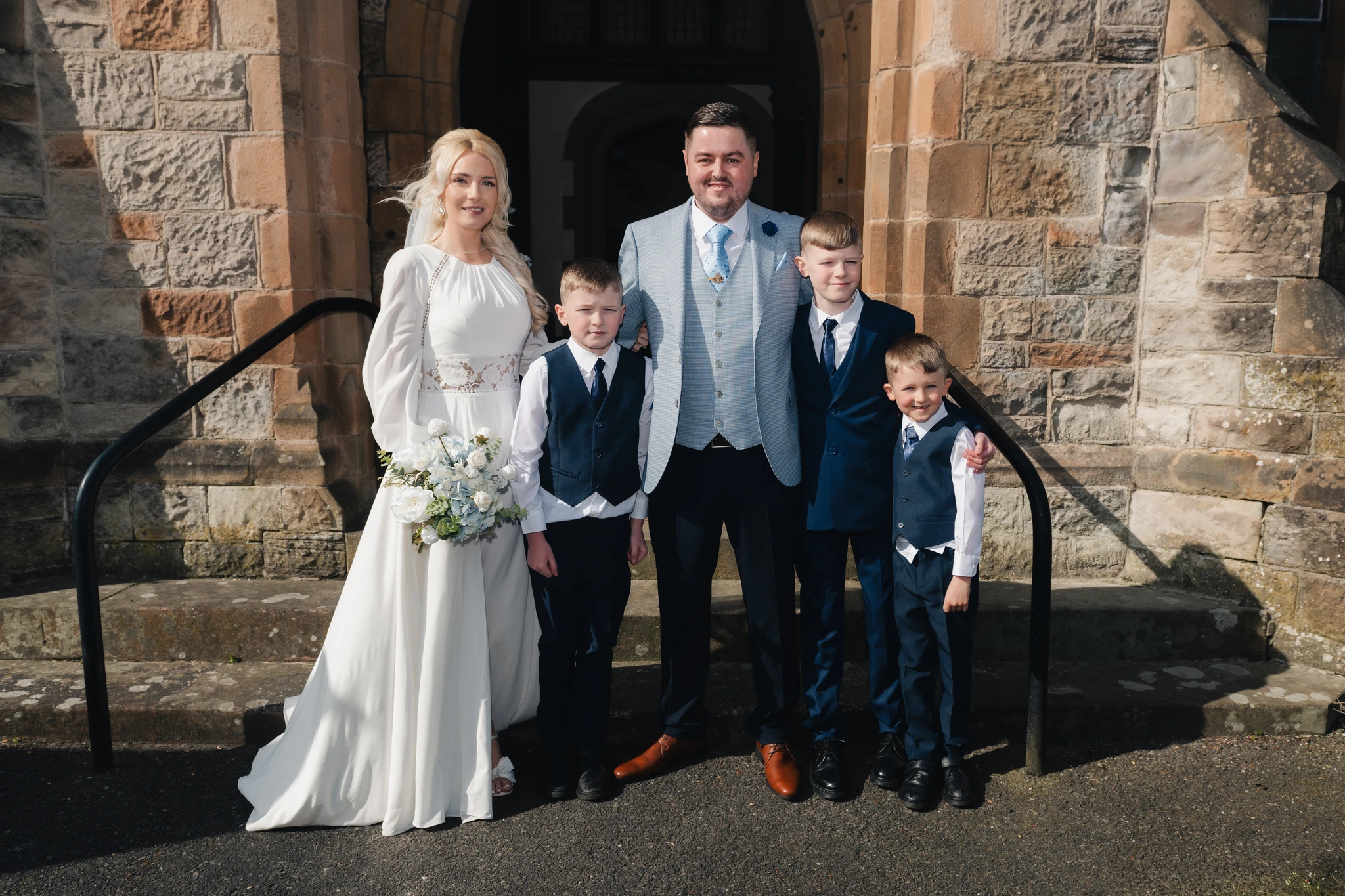 a bride and groom pose with their wedding party in front of a church