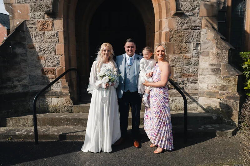 a bride and groom pose in front of a church