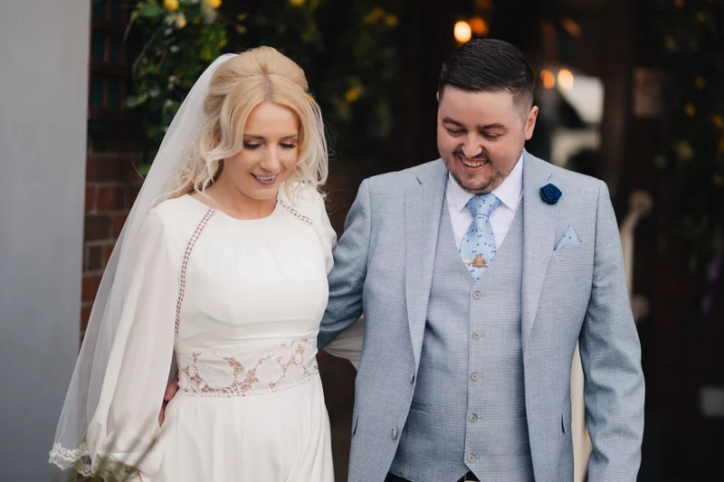 a bride and groom smile at each other as they walk down the aisle