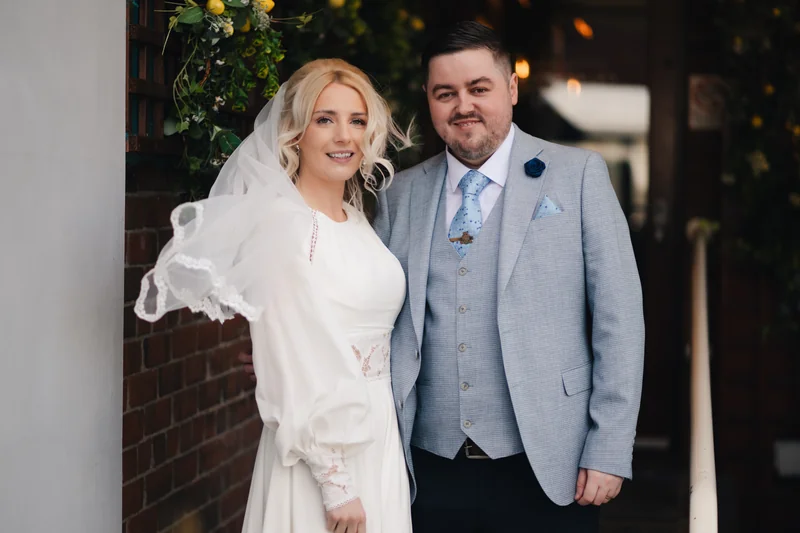 a bride and groom pose for a photo in front of their wedding venue