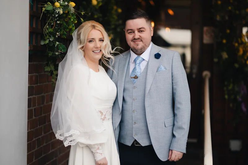 a bride and groom pose for a photo in front of their wedding venue