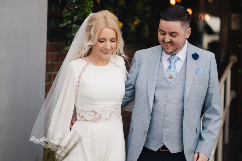a bride and groom smile at each other as they walk down the aisle