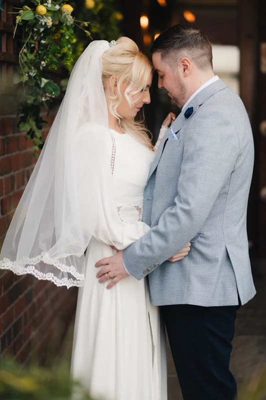 a bride and groom embrace in front of their wedding venue