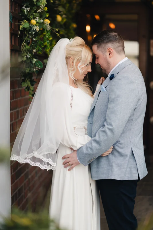 a bride and groom embrace in front of their wedding venue