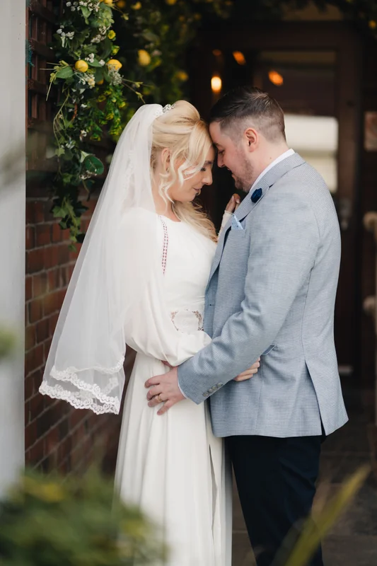a bride and groom embrace in front of their wedding venue