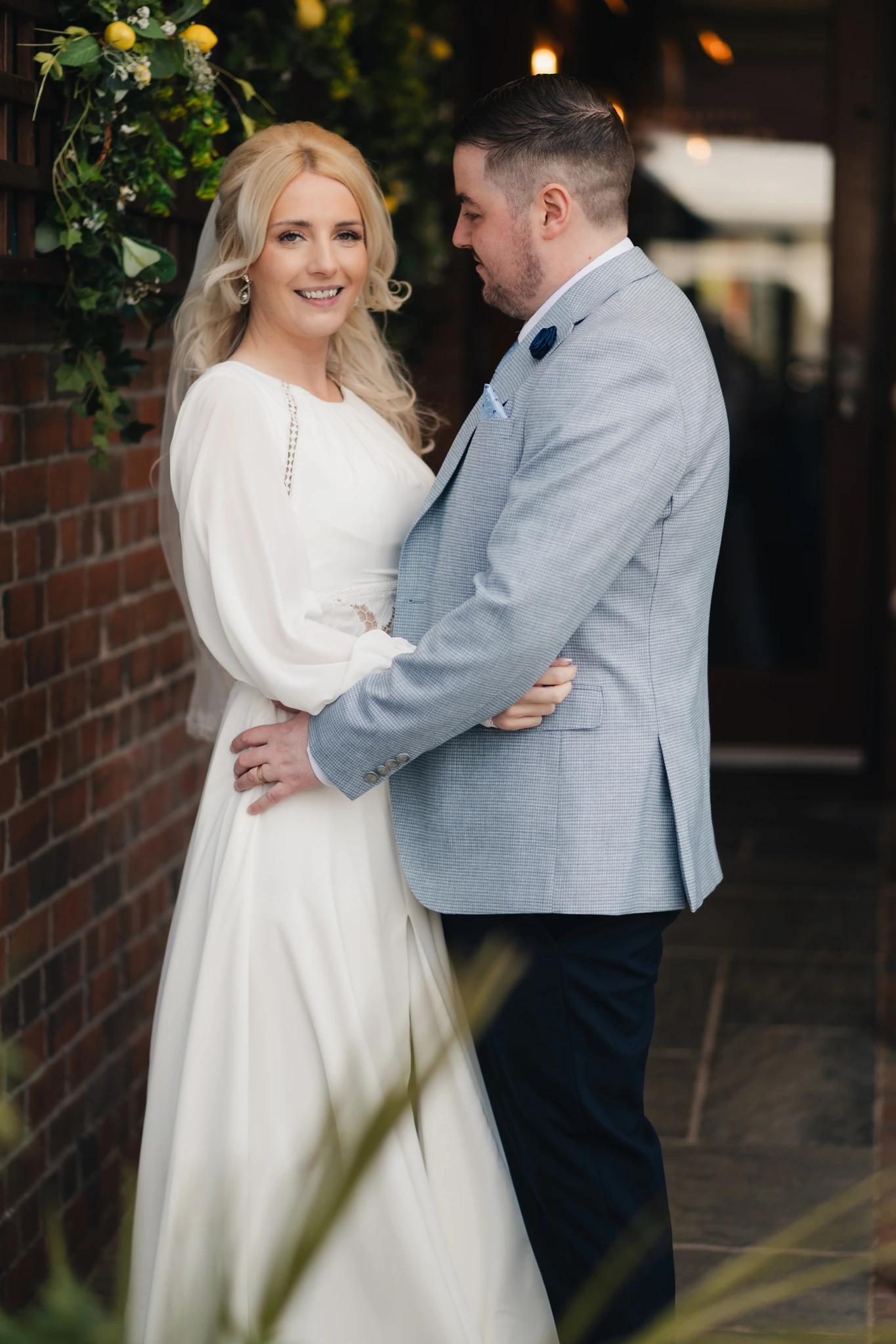 a bride and groom embracing in front of a window at their wedding venue
