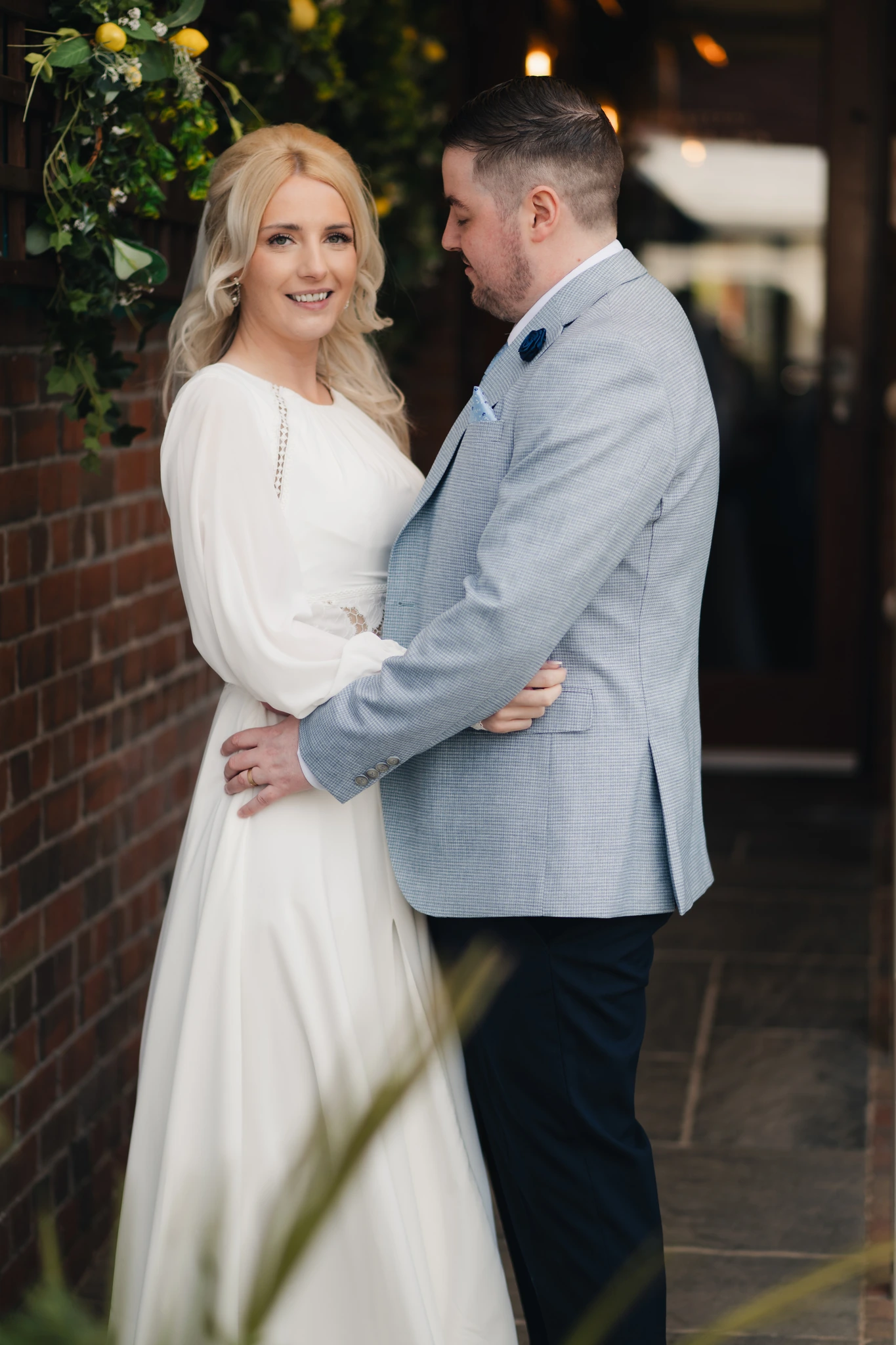a bride and groom embrace in front of their wedding venue